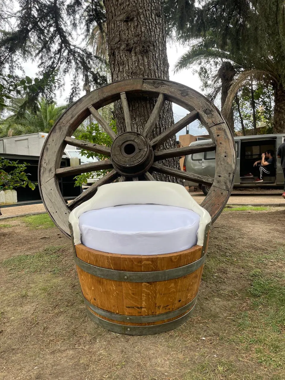 Sillón de barrica tapizado frente a una rueda de carreta