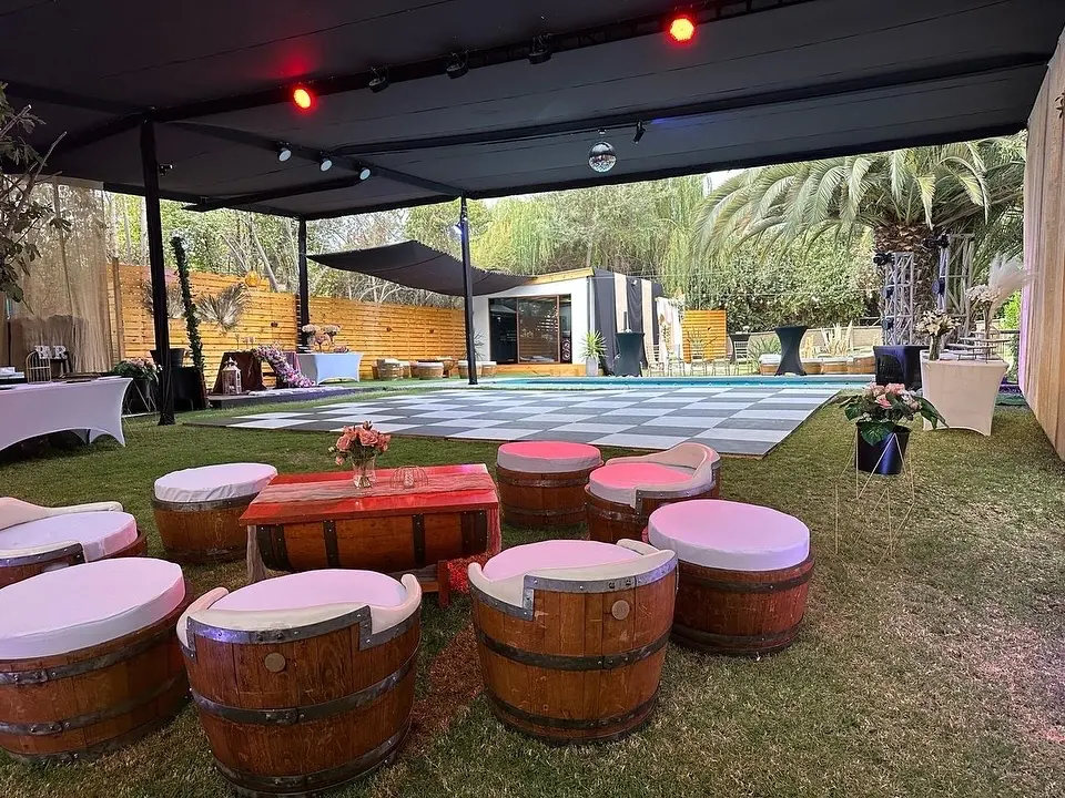 Mesas y asientos de barrica preparados bajo una carpa de evento